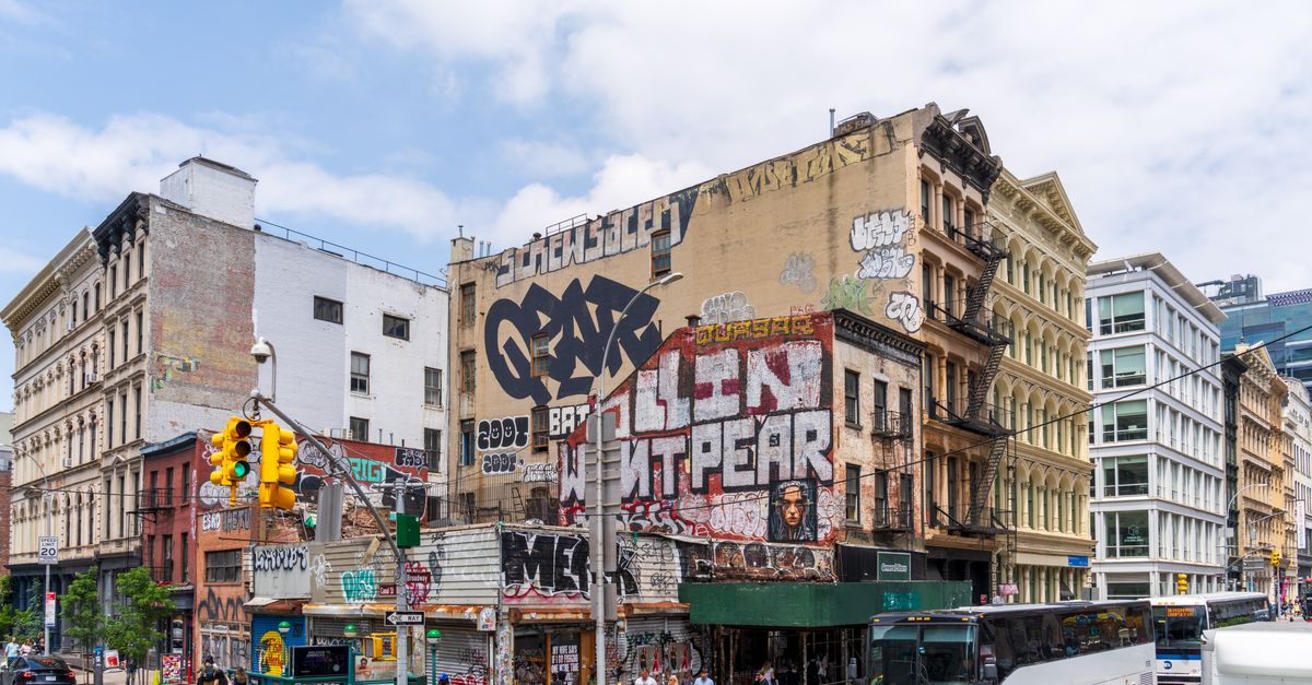 Vibrant street art and bustling urban scene in Soho, New York City, with pedestrians and traffic.
